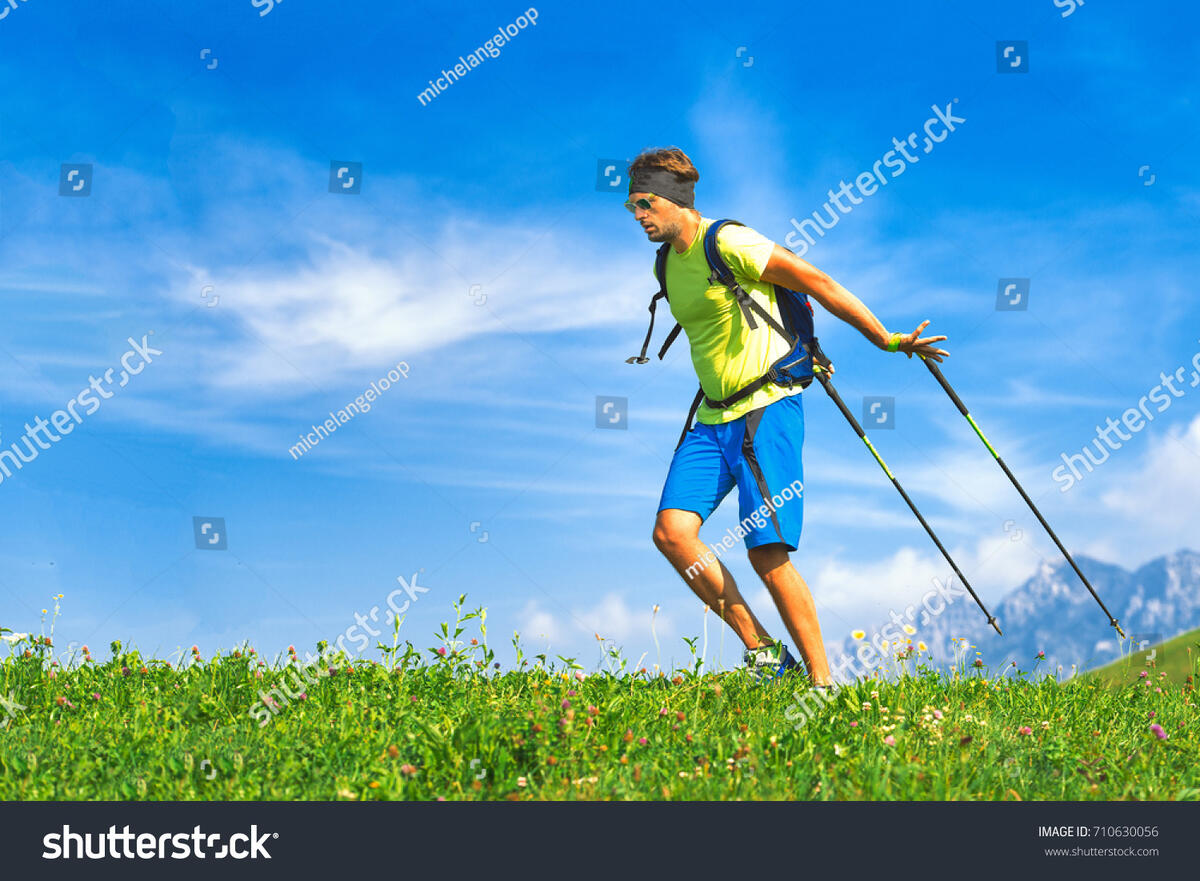 A hiker cresting a green hillside under an open blue sky